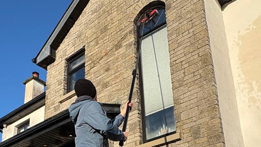 Cleaning windows of second storey house with water pole